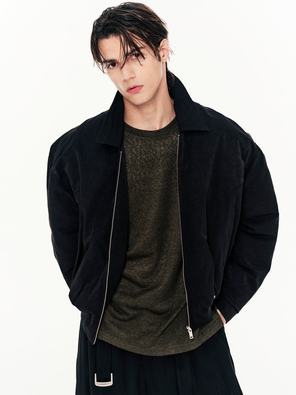 Person wearing a black jacket over a dark shirt on a white background