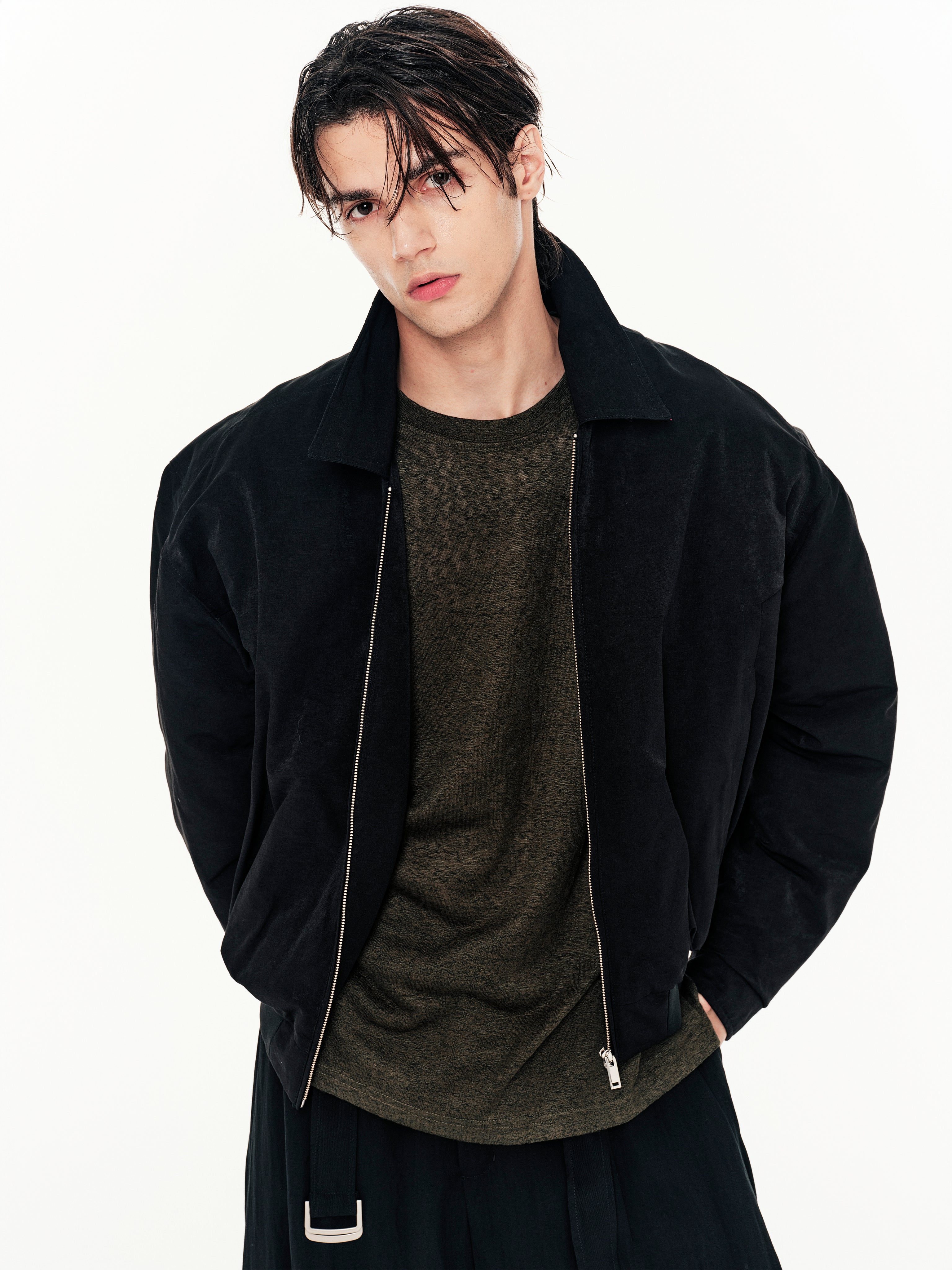 Person wearing a black jacket over a dark shirt on a white background