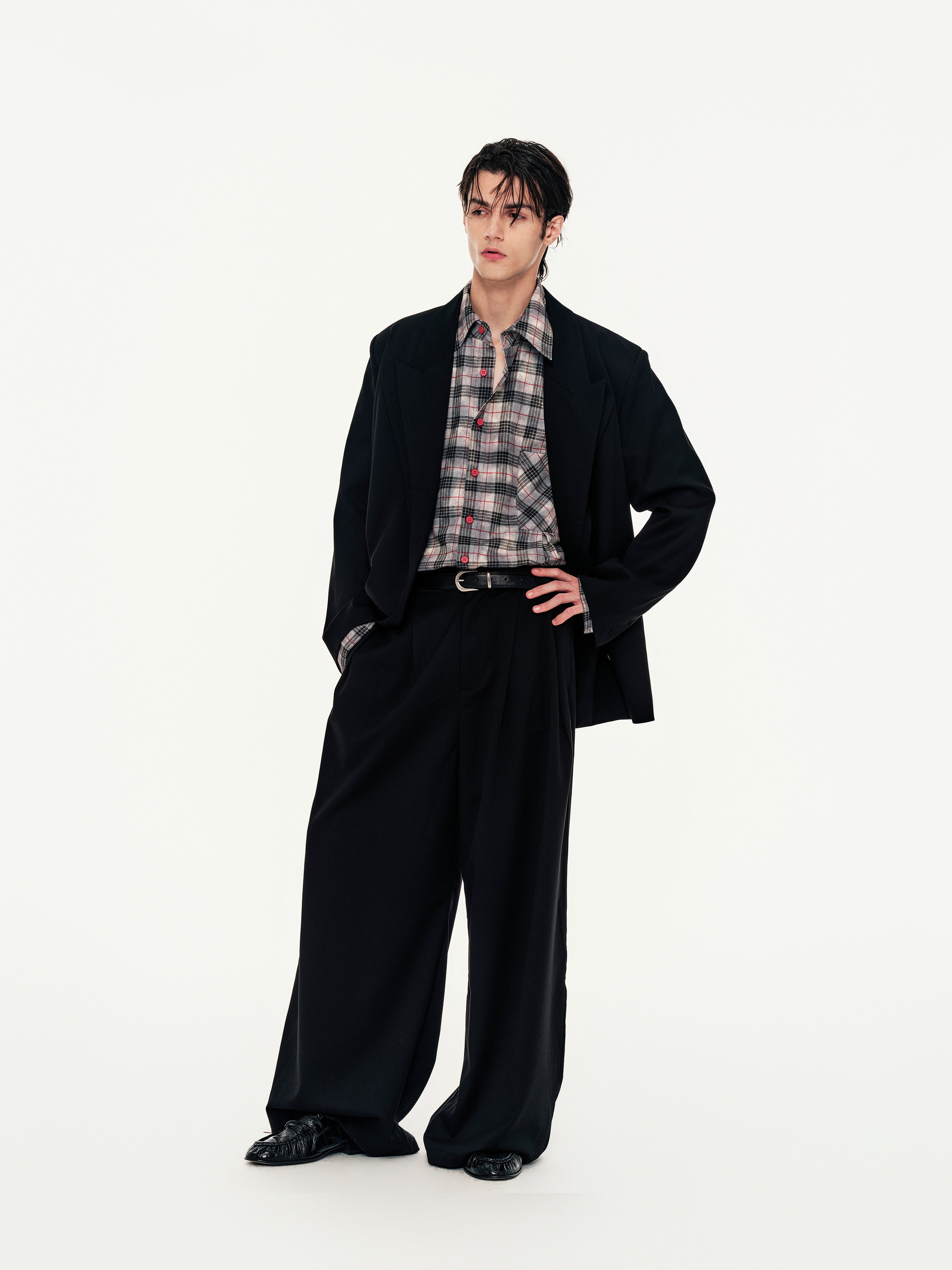 Person wearing a black suit with a plaid shirt on a white background