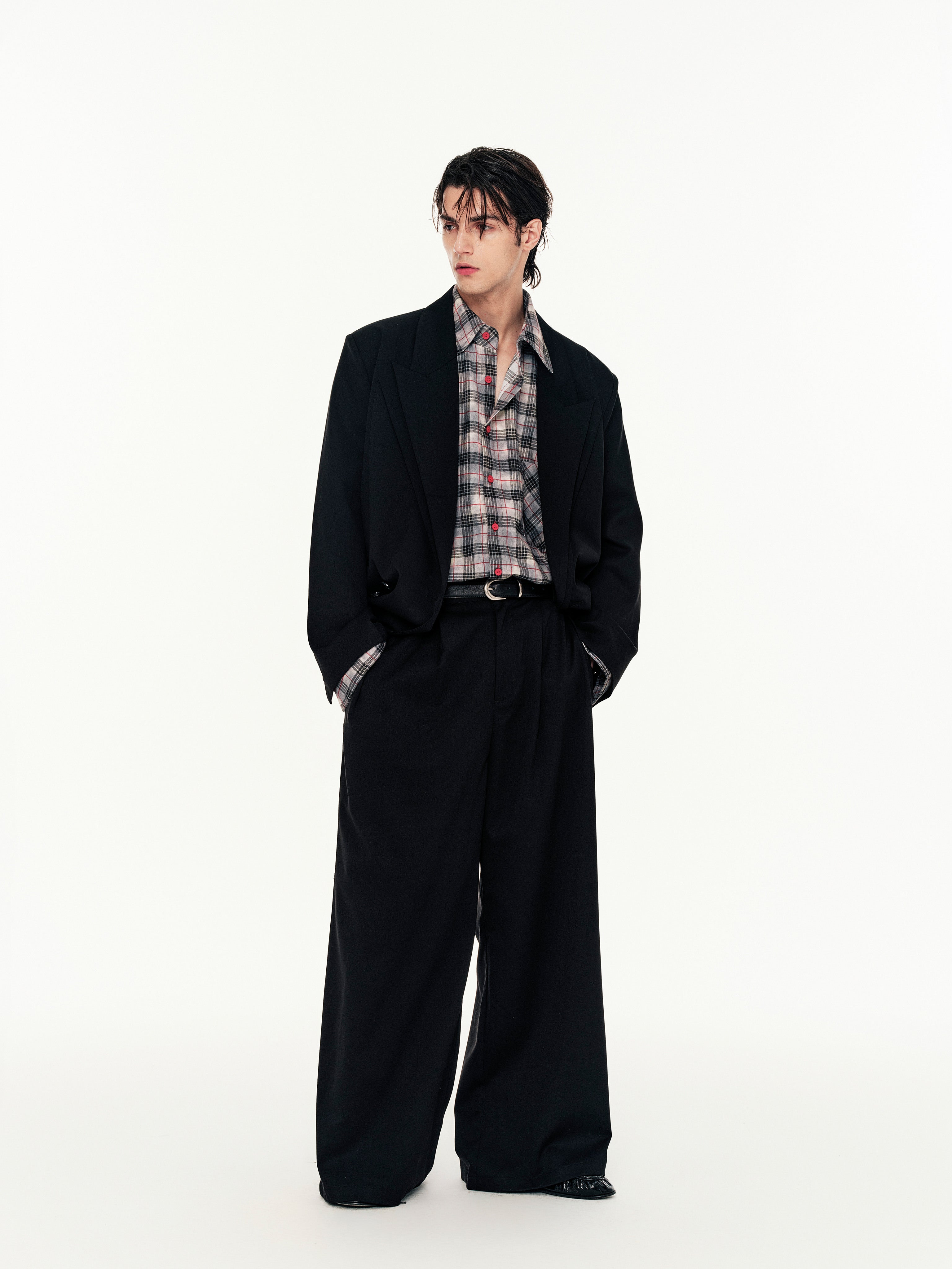 Person wearing a black suit with a plaid shirt on a white background