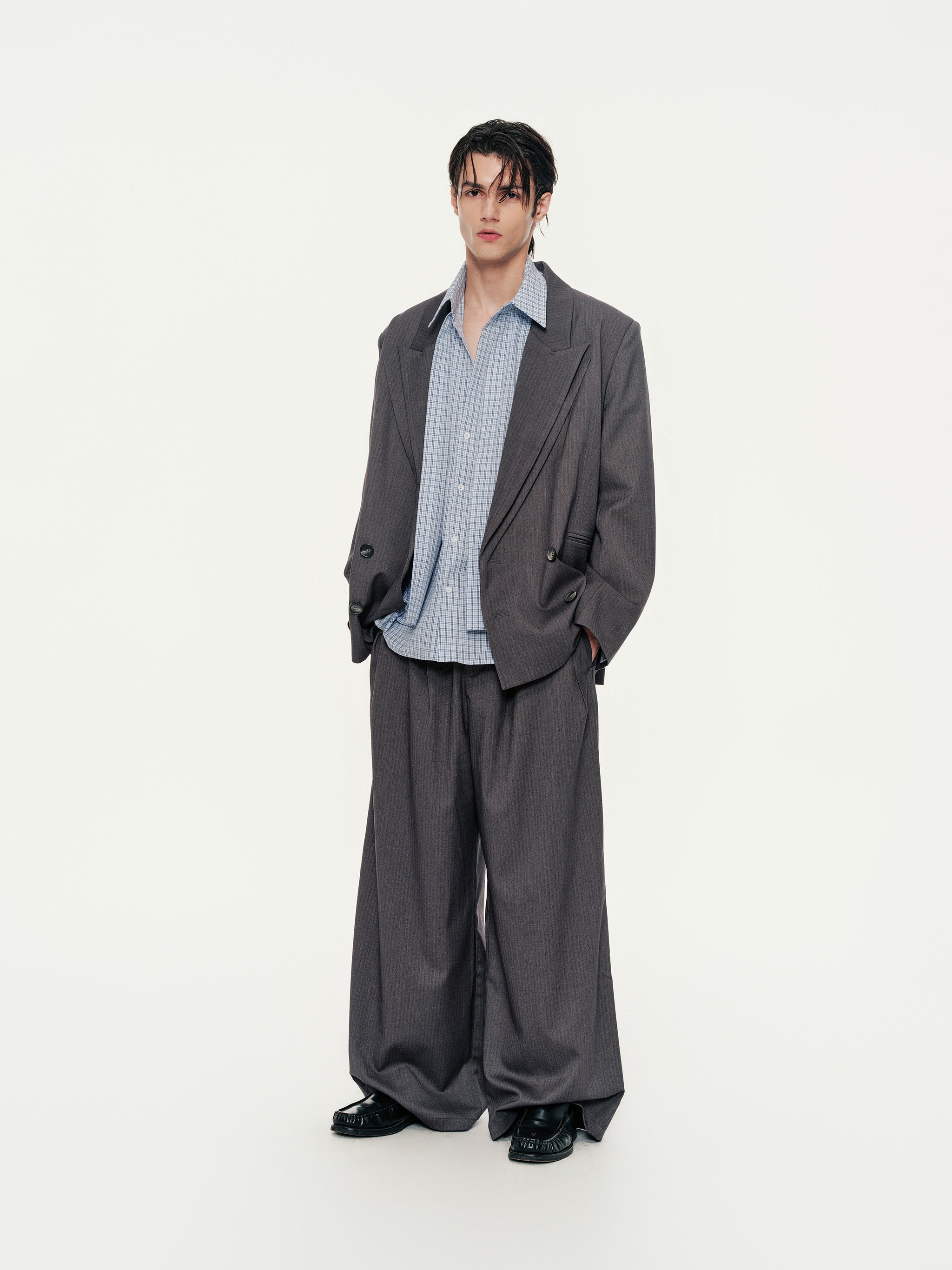 Man wearing a gray suit with a blue-grid shirt on a white background