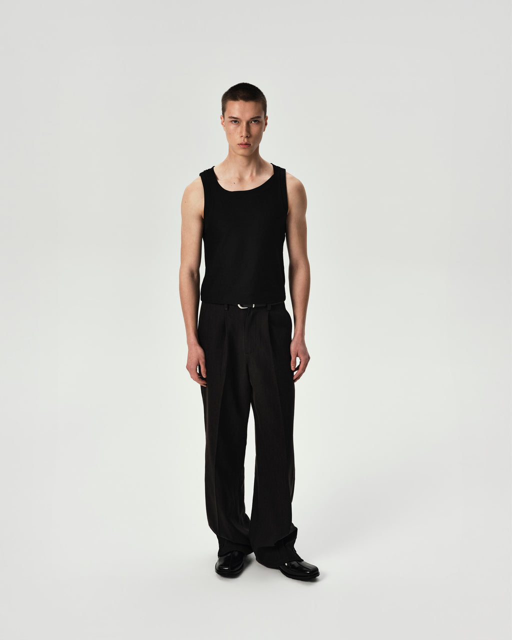 Person wearing a black tank top and pants on a white background