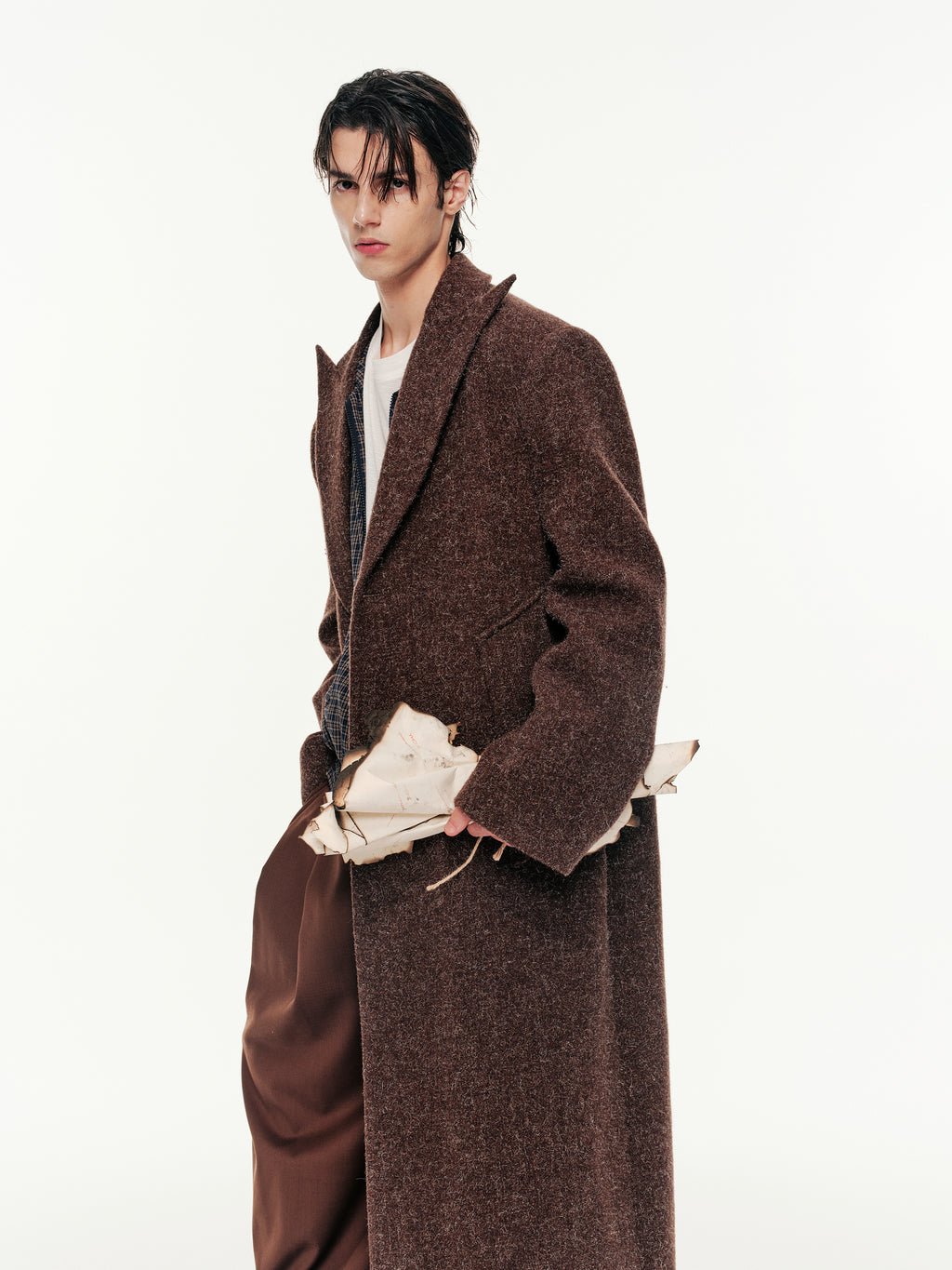 Person wearing a long brown coat on a white background
