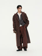 Person wearing a long brown coat and pants on a white background