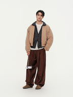 Person wearing a beige jacket with plaid shirt and brown pants on a white background